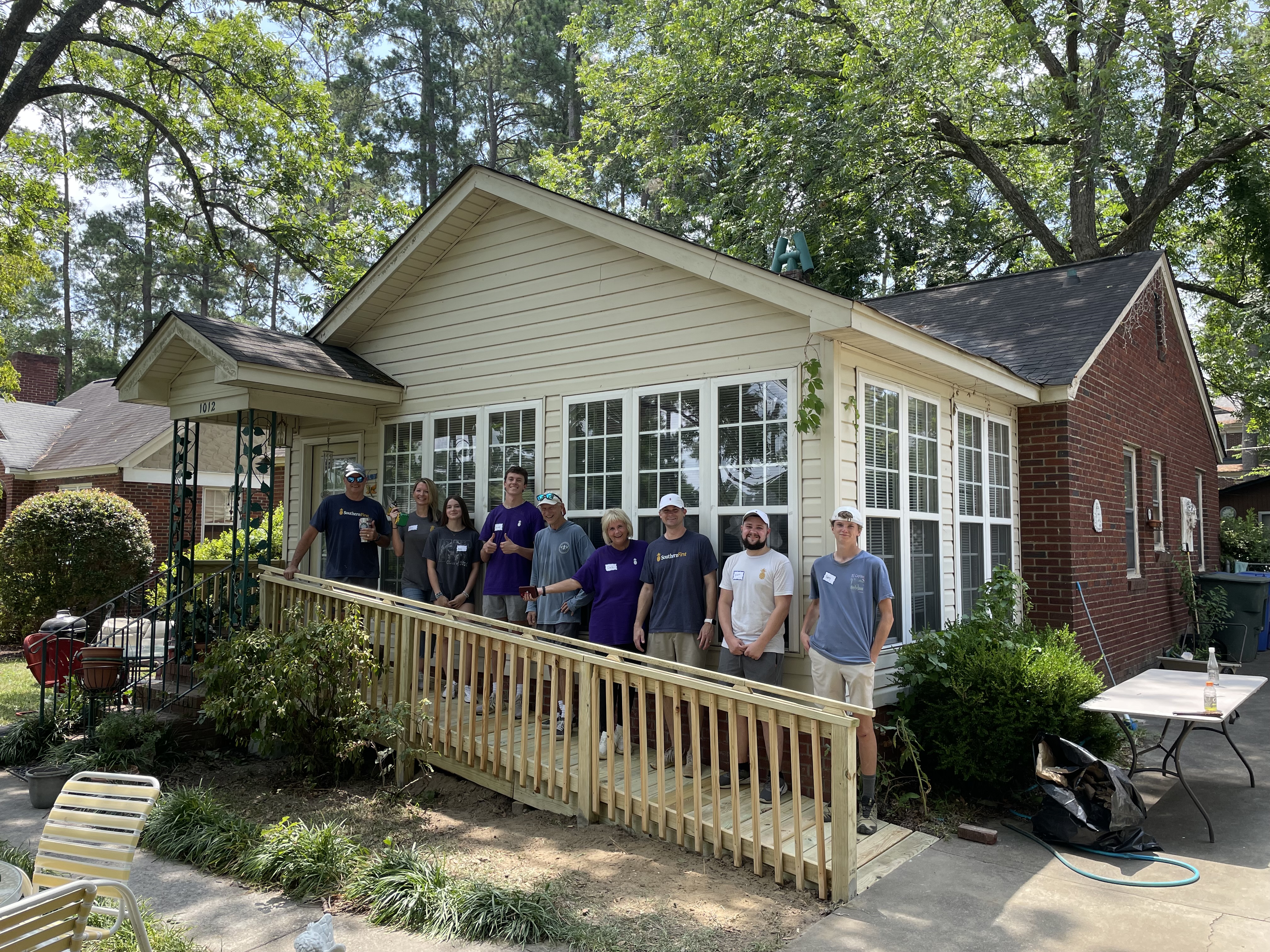 A group of Southern First bankers standing on a ramp in front of a home they built volunteering with Homeworks.