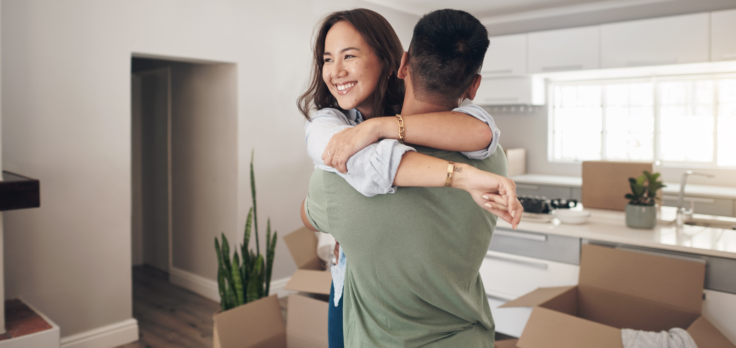 First-time homebuyer couple hugging in their new home.