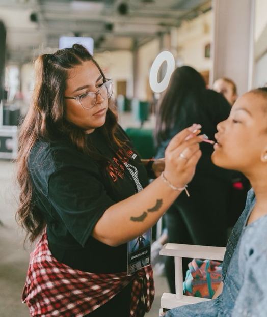 Virtual Experience Officer Val Gonzalez doing makeup on a model.