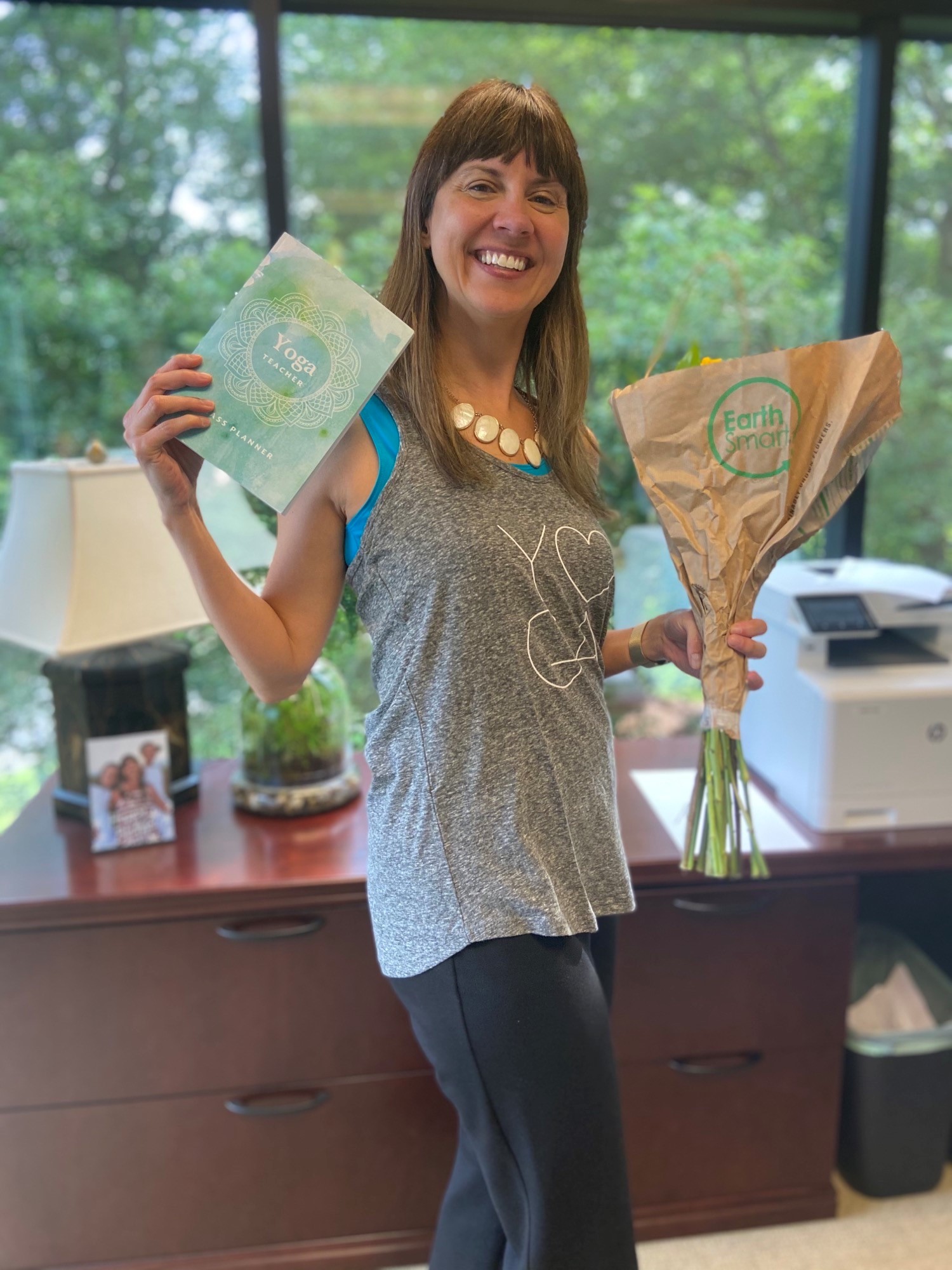 CHRO, Silvia King, holding up flowers and her yoga teacher certification.